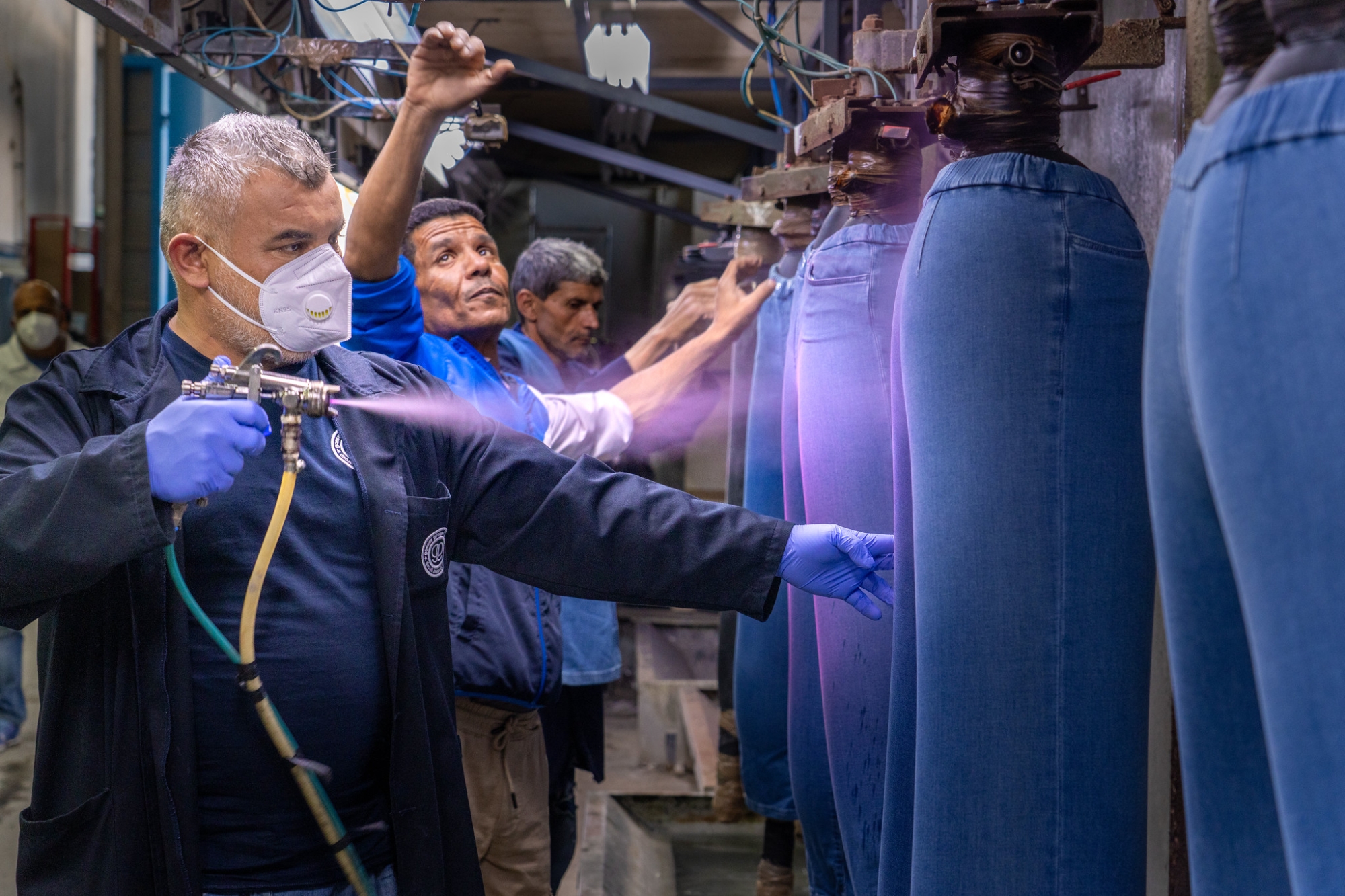Un hombre rocía tinte sobre unos jeans.