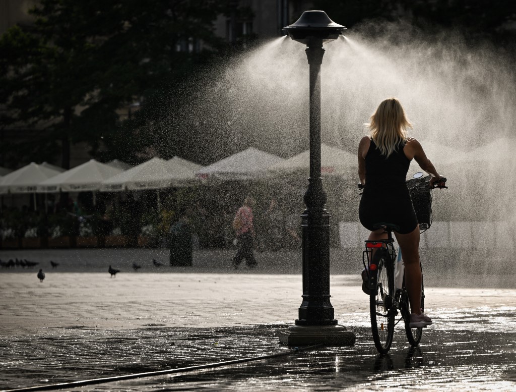A person riding a bike through a water sprayer