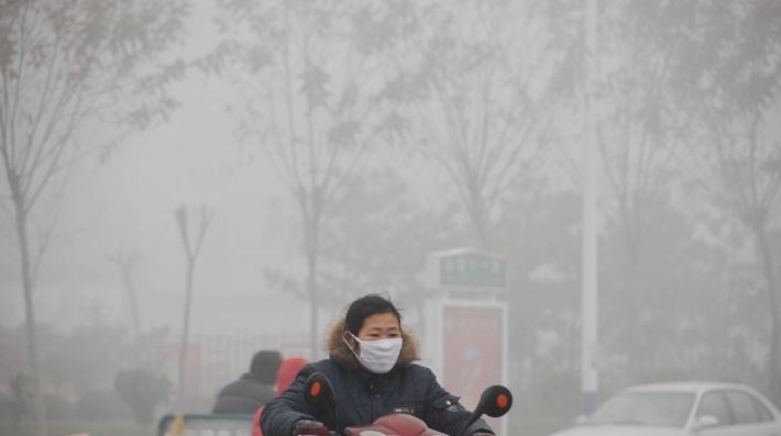 A woman wearing a mask on a motorbike