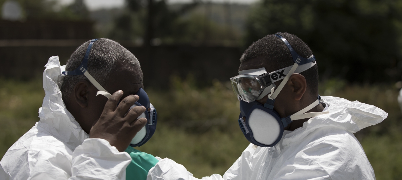 Two workers helping each other wearing protective equipment