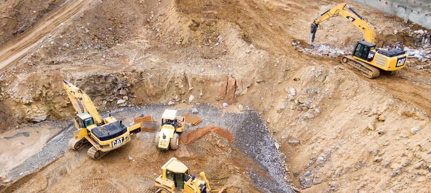 Top view photography of four heavy equipment on quarry at daytime