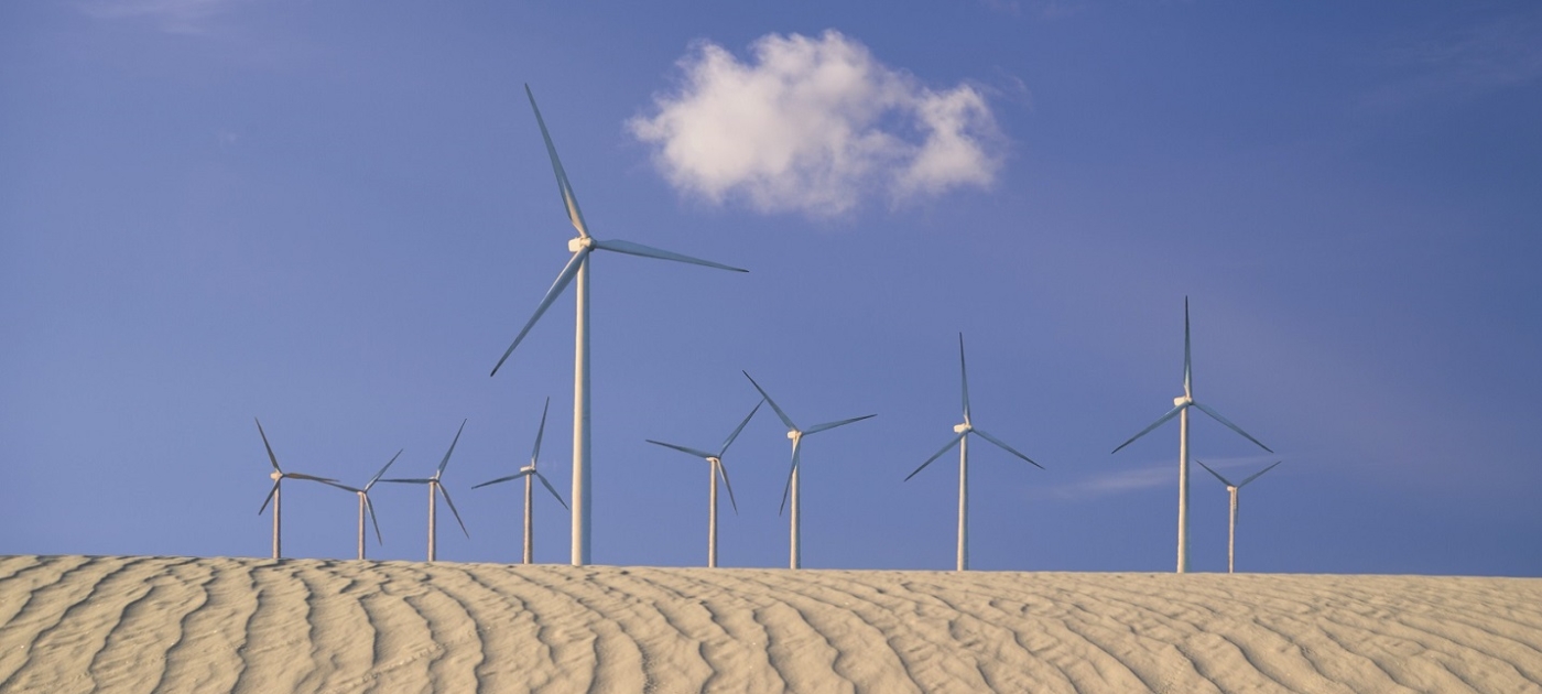 Wind turbines in the background of a sand dune