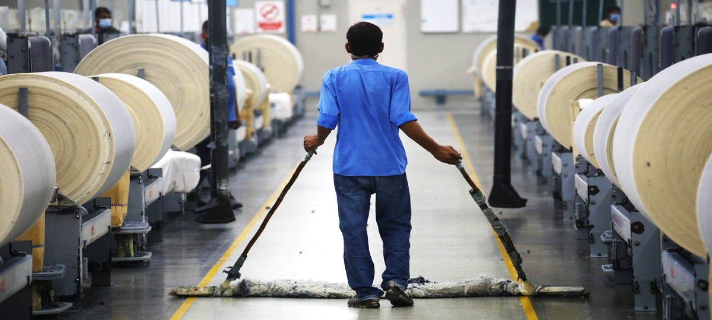 A person walks between fibre rolls in textile manufacturing plant