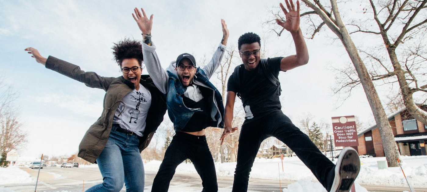 Young people jumping near bare trees during daytime