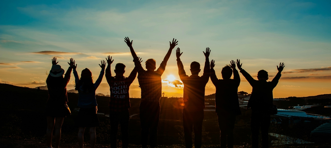 Youth group looking at the sunset with arms lifted high