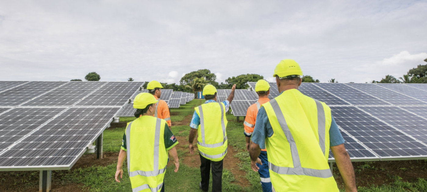 People walking through a field with solar panels