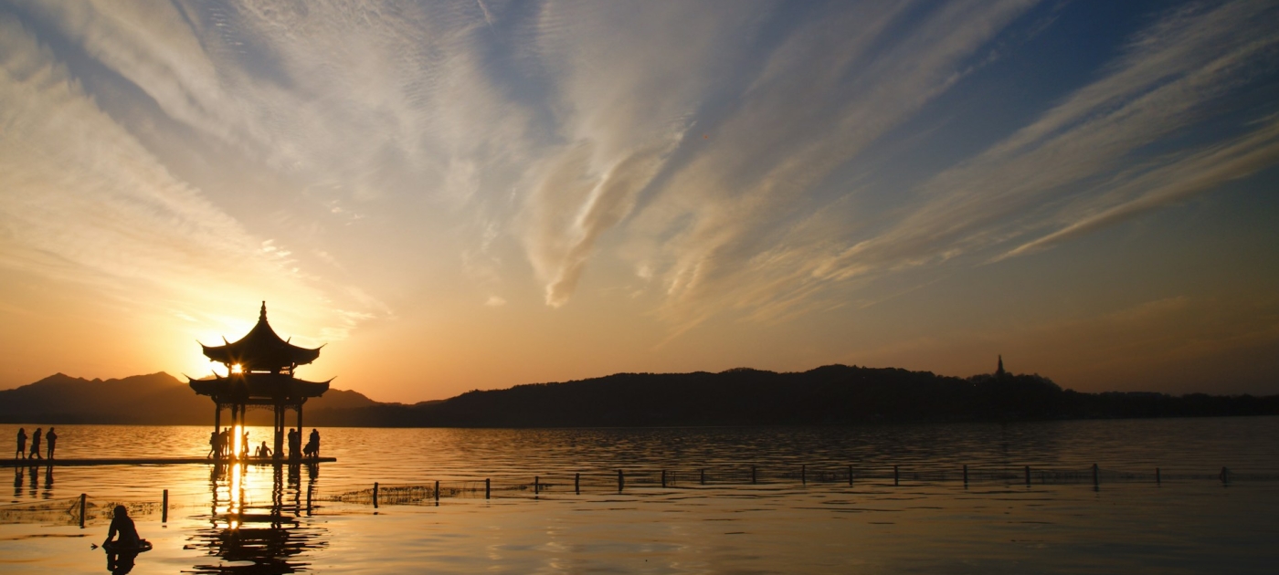 Silhouette of house on water during sunset