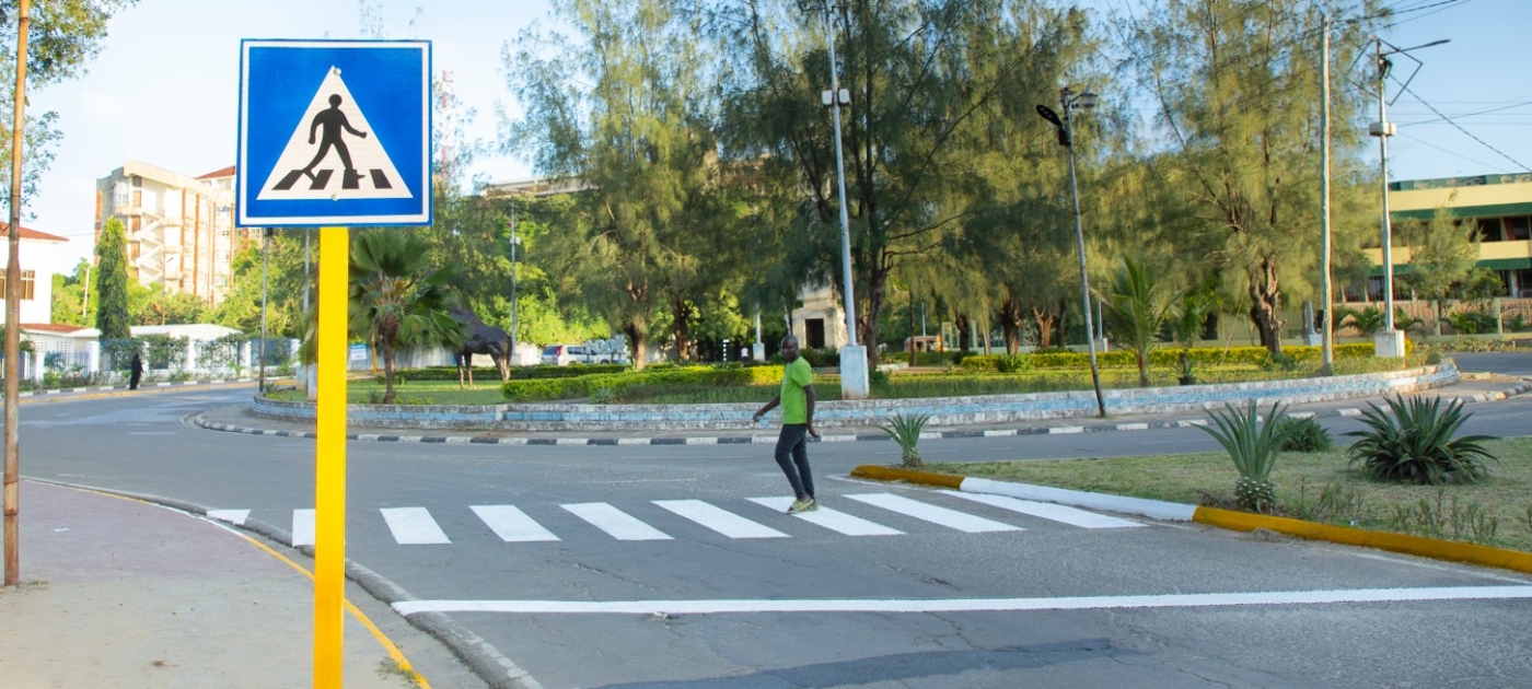 A person crosses the street at a zebra crossing