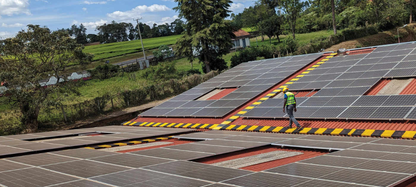 A worker crosses a roof full of solar panels