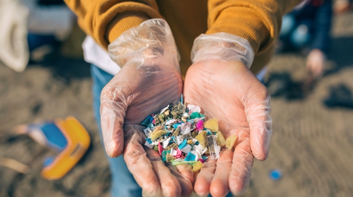 Hands showing microplastics on the beach 