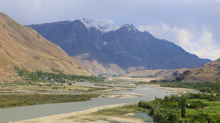 A mountain and river surrounded by fields.