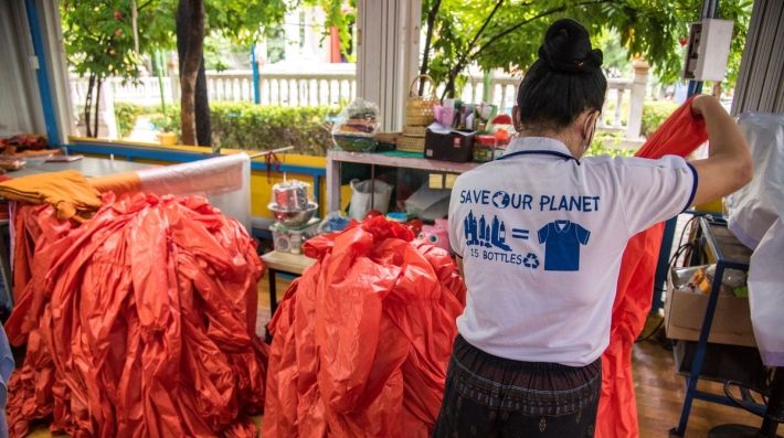 A young woman sorts clothes made of recycled plastic