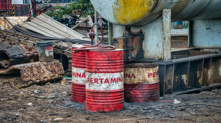 Aged metal barrels on a dirty landfill.