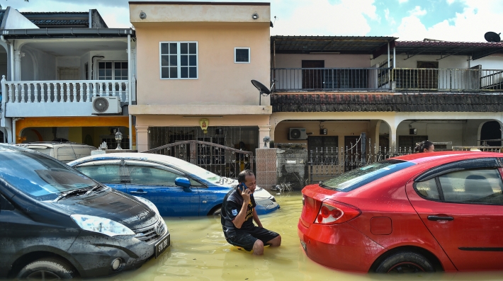 A man talking on a phone in knee-high floodwaters