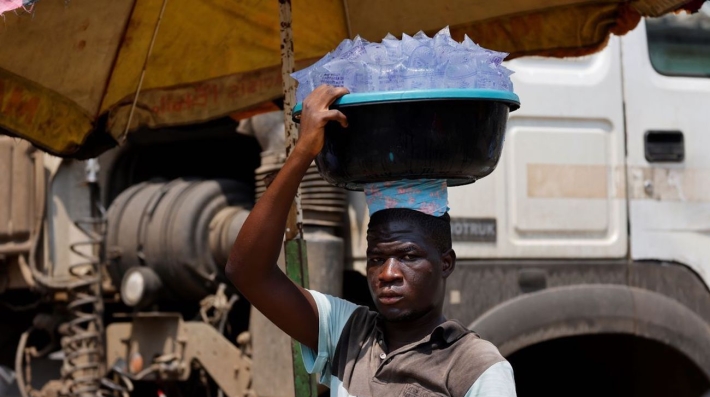 A street vendor carries water sachets on his head at the Mont Bouet market in Libreville 