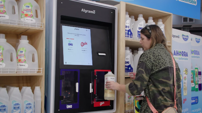 A woman refills a reusable detergent bottle at an Algramo machine.