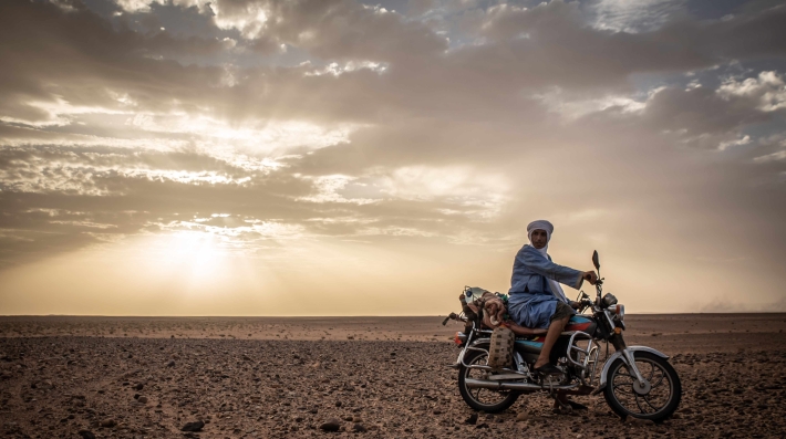 A Bedouin on a motorcycle in the Sahara, Morocco.