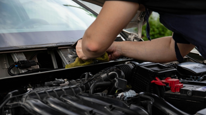 A mechanic tweaking a lead-acid battery in a car  