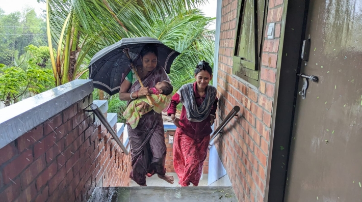 Prova Midhra and her family outside their new climate-resilient house 