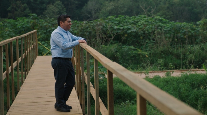 Homem em uma ponte cercada por árvores.