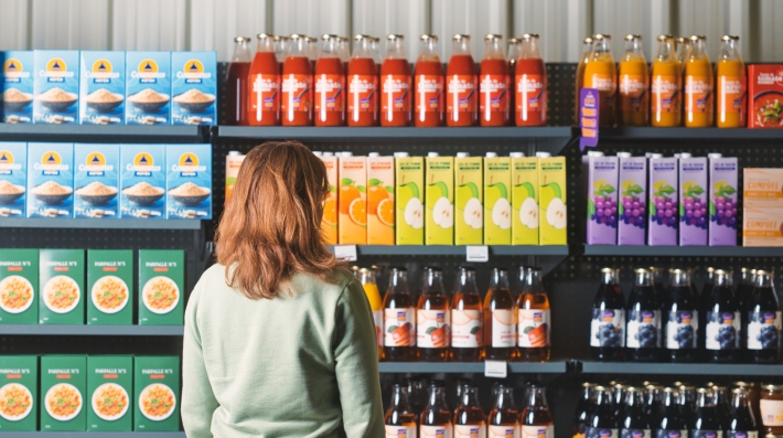 Woman stands in front of shelves with juice stored in reusable packaging