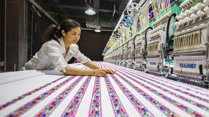A woman hovers over textiles in a factory