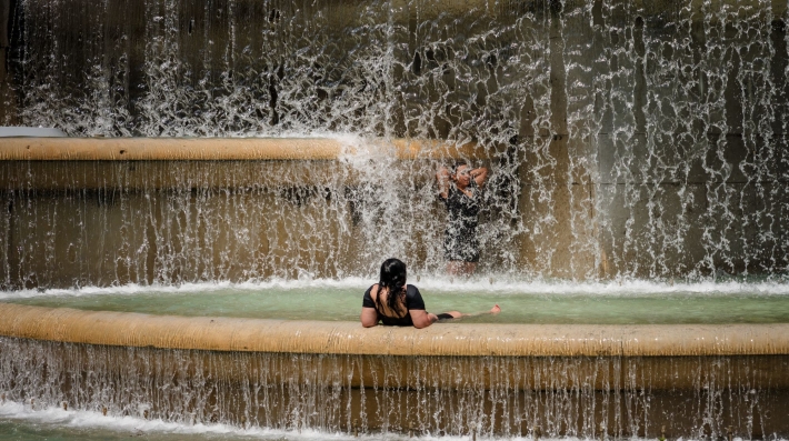 A woman cools herself off in a fountain