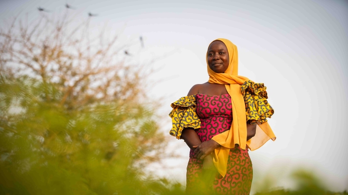 A woman standing near a shrub.