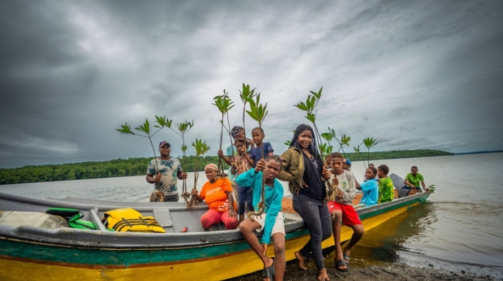 Niñas y niños de Cuerval, Colombia, con plantones en mano para reforestar un manglar. Los manglares se encuentran entre los sumideros de carbono más poderosos del mundo, ya que almacenan más carbono por hectárea que muchos bosques terrestres.