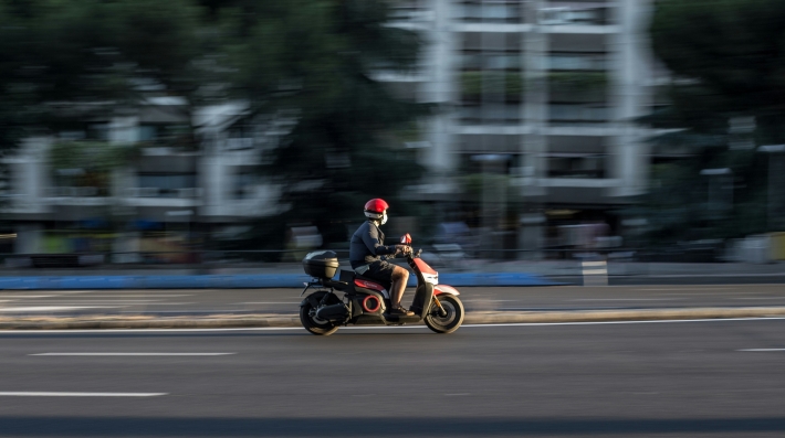 Un hombre conduce una moto en una calle.