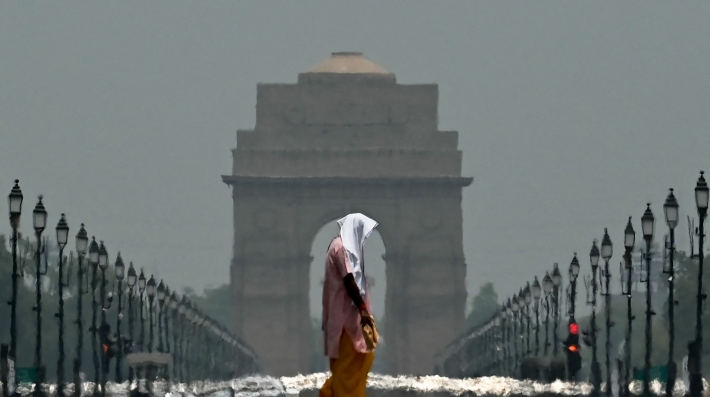 A woman walks in front of a monument with heat ripples in the background
