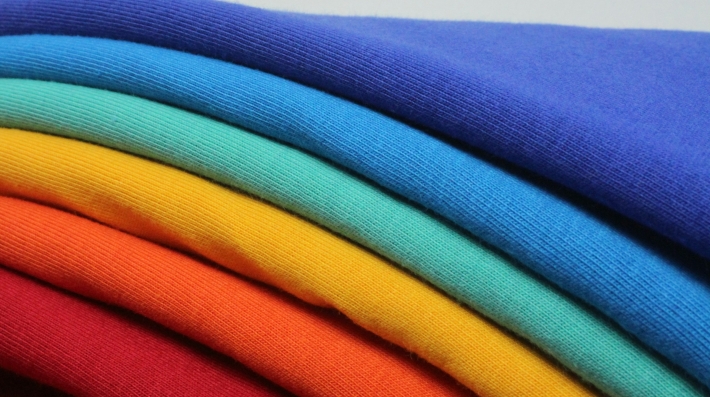 A stack of different colored t-shirts sitting on top of each other