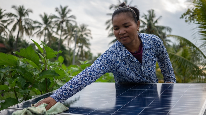 A woman is cleaning a solar panel in a farm