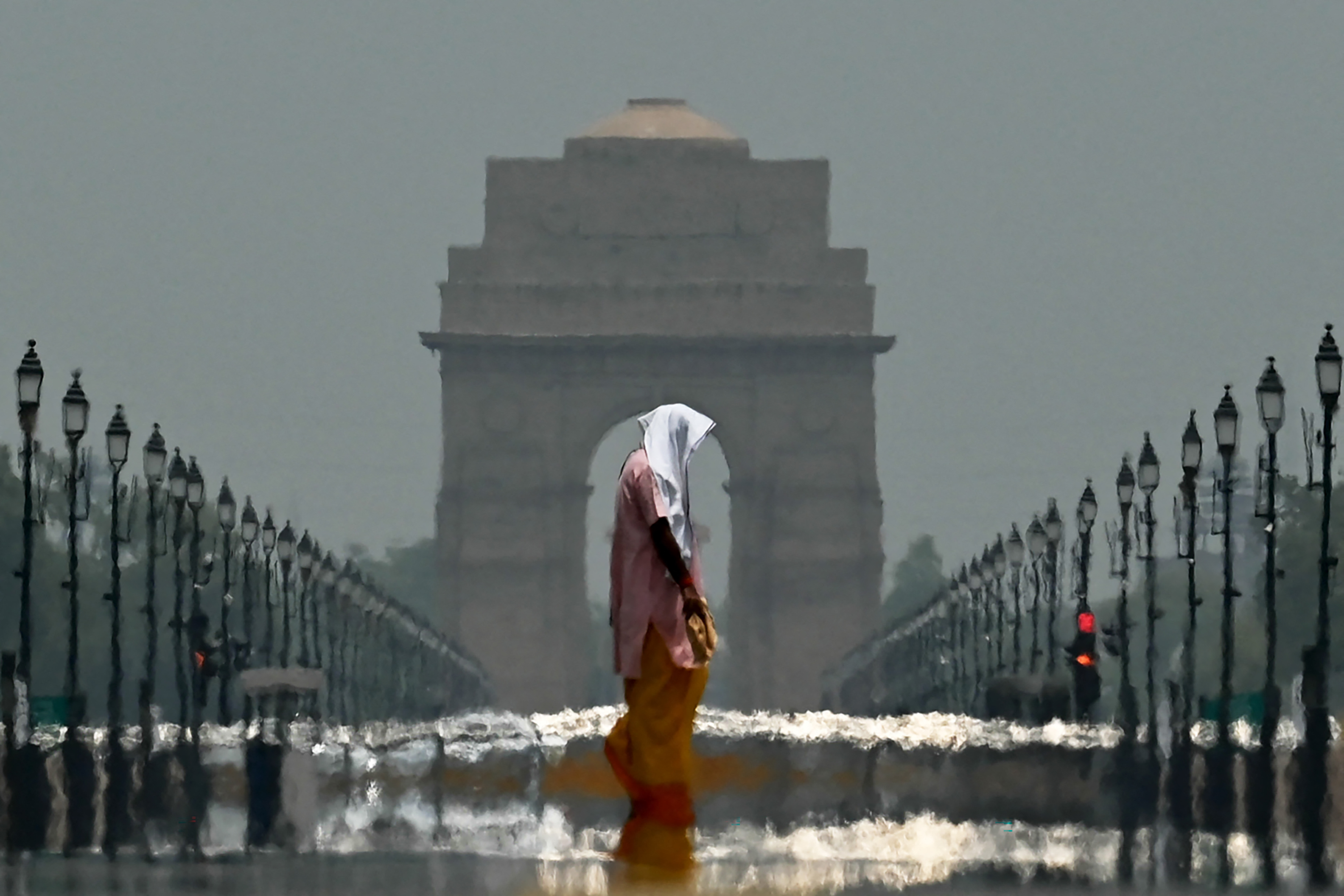 A woman walks in front of a monument with heat ripples in the background